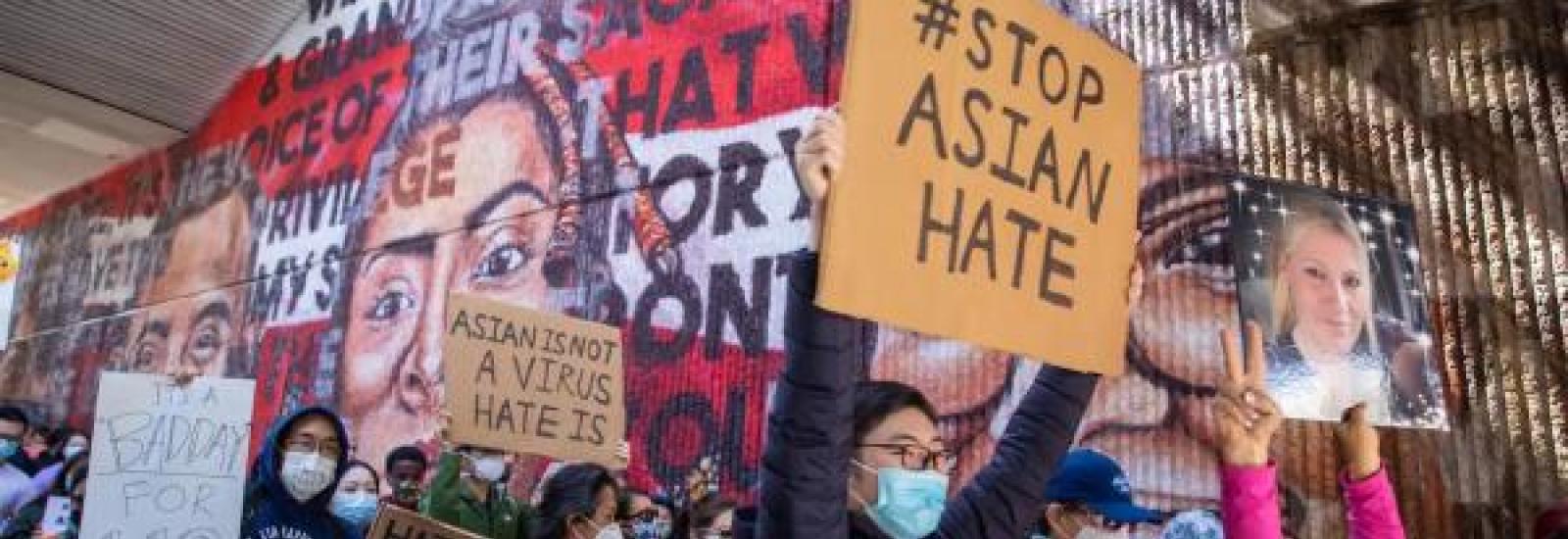 People at a small protest with signs that say stop Asian hate